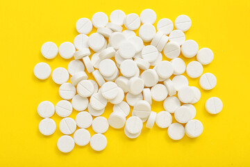 Wall Mural - Heap of white pills on yellow background