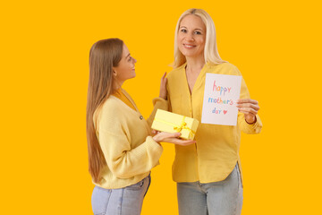 Sticker - Young woman greeting her mother with card and gift on orange background