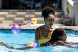© Wavebreak Media - Happy biracial mother and daughter learning to swim in swimming pool in sunny garden
