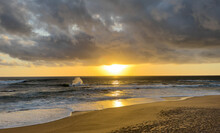 Sunset On The Atlantic Coast Of Portugal, With The Sun Sandwiched Between Dark Clouds And The Ocean
