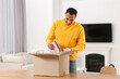© New Africa - Happy young man opening parcel at table indoors. Internet shopping