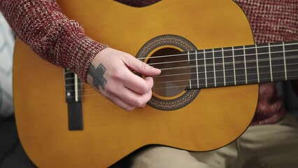 Poster - Young bald man playing classical guitar sitting on sofa at home