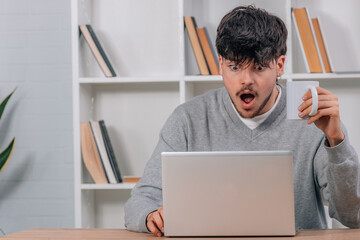 student at desk with computer or laptop amazed