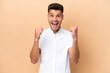 © luismolinero - Young caucasian man isolated on beige background celebrating a victory in winner position