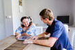 © Austockphoto - Teen wearing headphones talking with adult disability support worker in home office using tablet