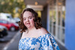 © Austockphoto - Smiling portrait of female teenager with down syndrome outside shops