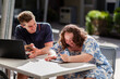 © Austockphoto - Happy young disability worker and his client with down syndrome working on devices at table