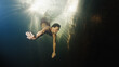 © Dudarev Mikhail - Man dives in the freshwater river with sunny rays shining through the water and swims near the rock