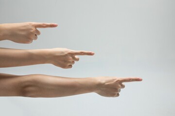 Wall Mural - Closeup shot of a bunch of hands pointing to something on a gray background with copy space