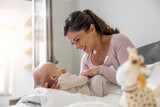 Fototapeta  - Portrait of beautiful mom playing with her three months old baby in bedroom