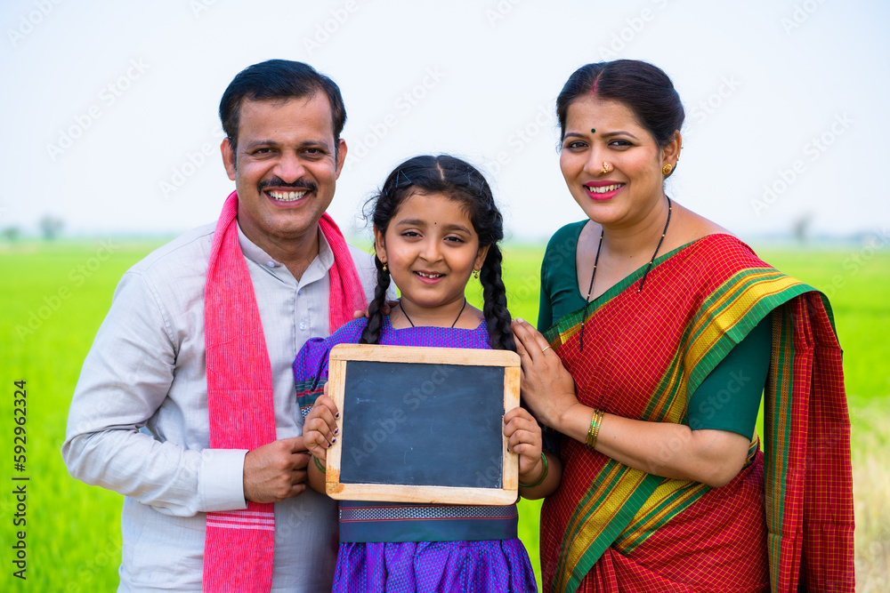 Happy smiling couple with girl kid showing empty slate board by looking ...