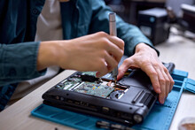 Cropped Professional IT Specialist Replacing Details In Computer Repair Workshop, Hardware Upgrading. A Real Case Of Service Assistance. Unrecognizable Male Sit At Work Place Repairing Old Laptop