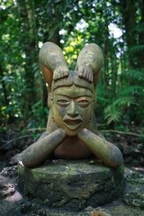 Canvas Print - Vertical closeup of an old Hindi statue covered in leaves and moss in the Jungle