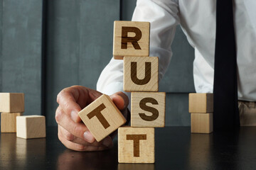 Build trust concept is shown using the text. Hand stacking wooden blocks with word trust