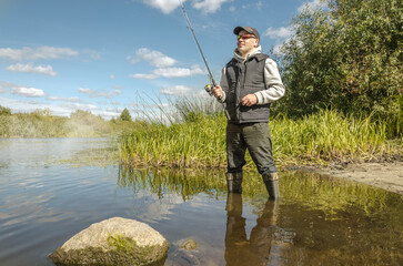 Fisherman in a hat on the river bank