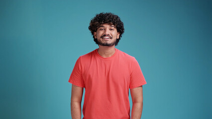 young smiling confident happy indian man 20s in basic coral t-shirt hold look camera isolated on a b