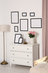 Sticker - Empty frames hanging on white wall and chest of drawers with flowers in room