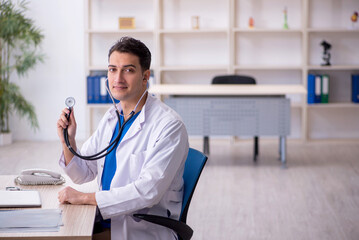 Wall Mural - Young male doctor sitting in the clinic