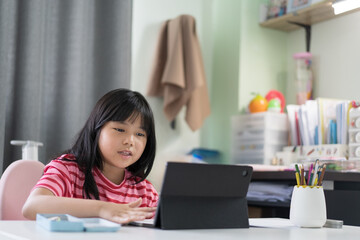 Wall Mural - asian child back to school and smile study online class on computer tablet or kid girl student video call studying or person happy learn from home by fun learning on pad in classroom at homeschool