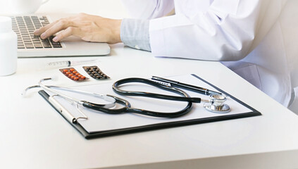 Close-up of stethoscope, paper, laptop on doctor table.