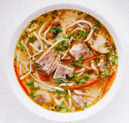 Chicken soup with noodles and vegetables in white bowl