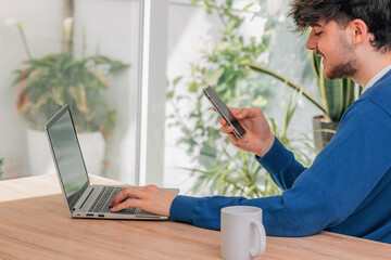 Canvas Print - young male student with mobile phone and laptop at desk