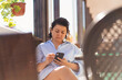 © andrey - Brunette woman middle-aged drinking coffee with phone on the terrace of house