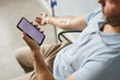 © Seventyfour - Closeup of unrecognizable man using smartphone with blank white screen during IV drip treatment, copy space