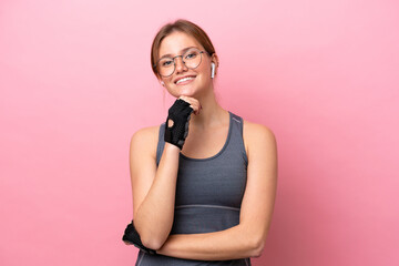 Wall Mural - Young sport caucasian woman isolated on pink background with glasses and smiling