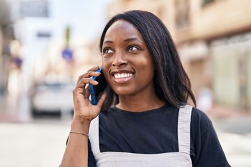 Wall Mural - Young african american woman smiling confident talking on the smartphone at street