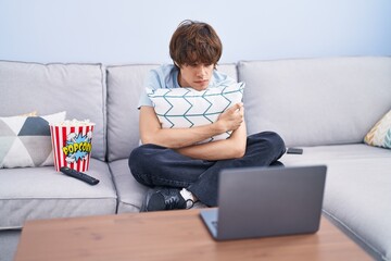 Poster - Hispanic young man watching a horror movie in the laptop skeptic and nervous, frowning upset because of problem. negative person.