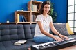 © Krakenimages.com - Young beautiful hispanic woman playing piano sitting on sofa at park