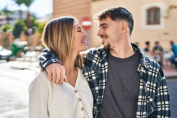 Wall Mural - Young man and woman couple hugging each other standing at street