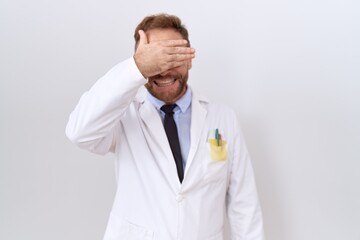 Poster - Middle age doctor man with beard wearing white coat smiling and laughing with hand on face covering eyes for surprise. blind concept.