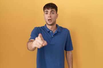 Sticker - Young hispanic man standing over yellow background pointing displeased and frustrated to the camera, angry and furious with you