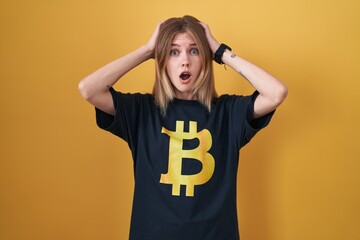 Canvas Print - blonde caucasian woman wearing bitcoin t shirt crazy and scared with hands on head, afraid and surpr