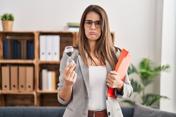 Poster - Beautiful woman working at therapy office holding sand clock depressed and worry for distress, crying angry and afraid. sad expression.