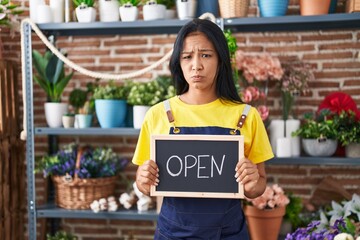 Poster - Hispanic woman working at florist holding open sign skeptic and nervous, frowning upset because of problem. negative person.