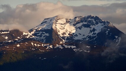 Canvas Print - Mountain peak covered in snow with a cloudy sky in the background, Norway