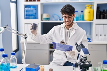 Canvas Print - Young hispanic man scientist weighing sample reading document at laboratory