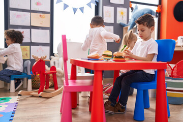 Poster - Group of kids playing with play food toy sitting on table at kindergarten