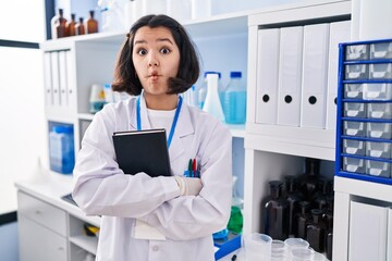 Poster - Young hispanic woman working at scientist laboratory making fish face with mouth and squinting eyes, crazy and comical.