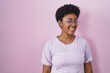 © Krakenimages.com - Young african american woman standing over pink background winking looking at the camera with sexy expression, cheerful and happy face.