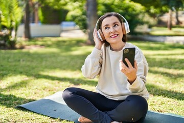 Sticker - Middle age woman listening to music sitting on herb at park