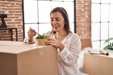 Wall Mural - Middle age woman smiling confident eating salad at new home