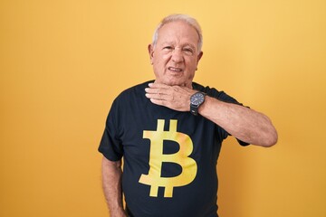 Canvas Print - Senior man with grey hair wearing bitcoin t shirt cutting throat with hand as knife, threaten aggression with furious violence