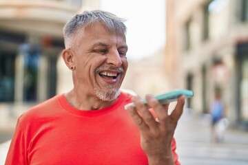 Sticker - Middle age grey-haired man smiling confident talking on the smartphone at street