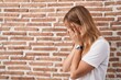 © Krakenimages.com - Young caucasian woman standing over bricks wall with sad expression covering face with hands while crying. depression concept.