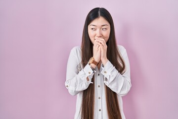 Poster - Chinese young woman standing over pink background laughing nervous and excited with hands on chin looking to the side