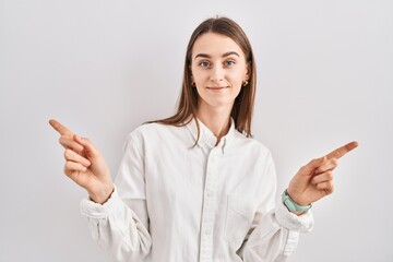 Sticker - Young caucasian woman standing over isolated background smiling confident pointing with fingers to different directions. copy space for advertisement